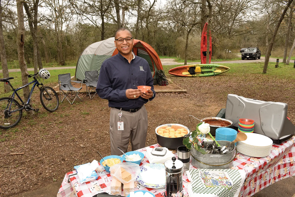 Rodney Frankling at a picnic table covered in food at a campsite