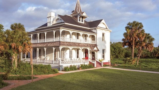 Two story home with wrap around porches and Sabal Palms