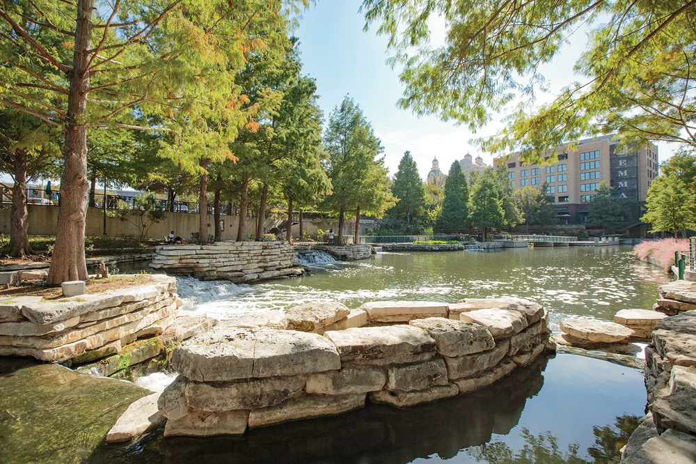 San Antonio River Walk with stone areas for sitting with office buildings in background