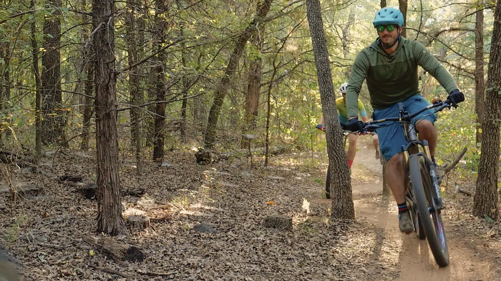 Man in biking gear riding on a trail through the woods