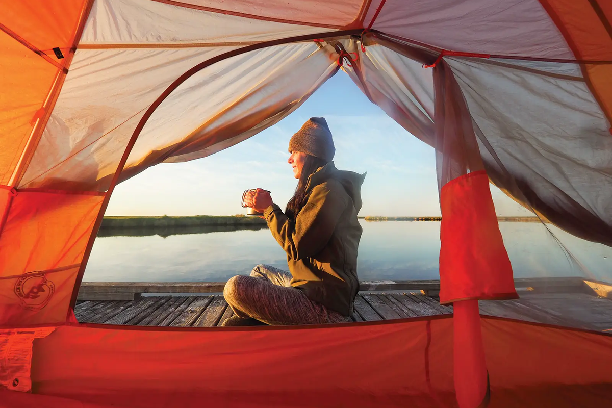 Sea Rim State Park woman in a tent on a floating platform drinking a beverage