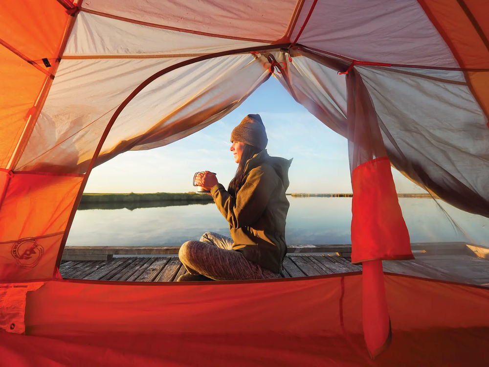 Sea Rim State Park woman in a tent on a floating platform drinking a beverage