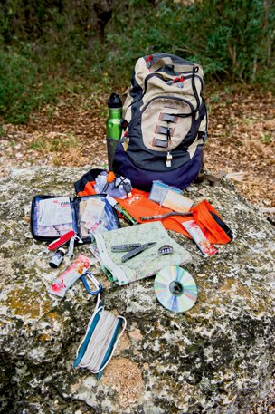 Supplies of a survival kit sitting out next to a backback