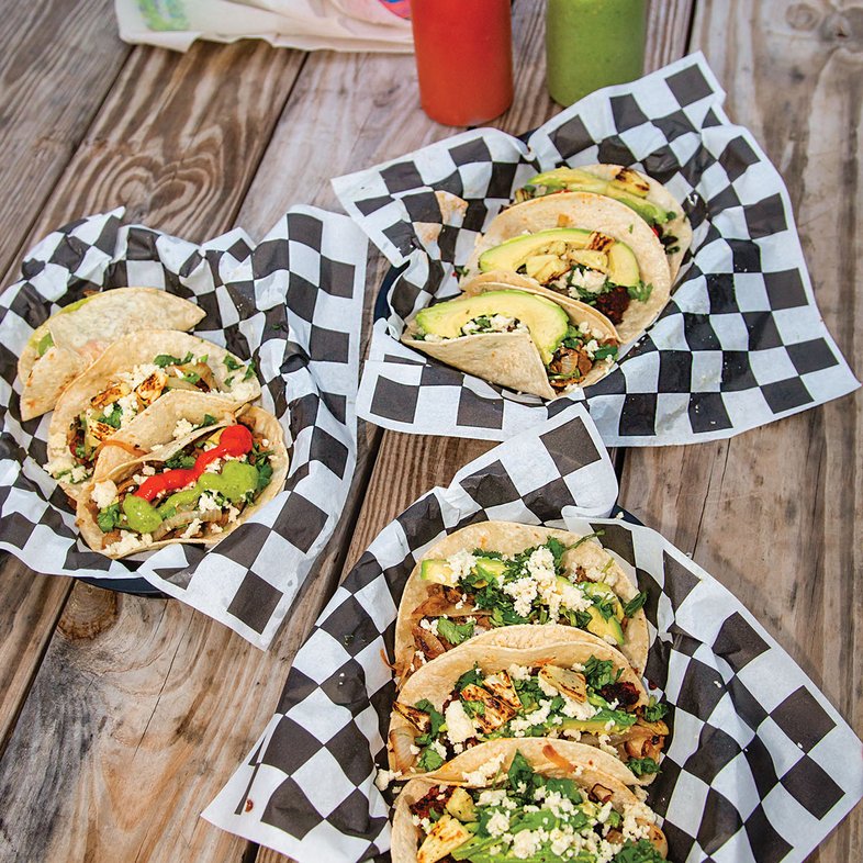 Tacos on plates on a picnic table.