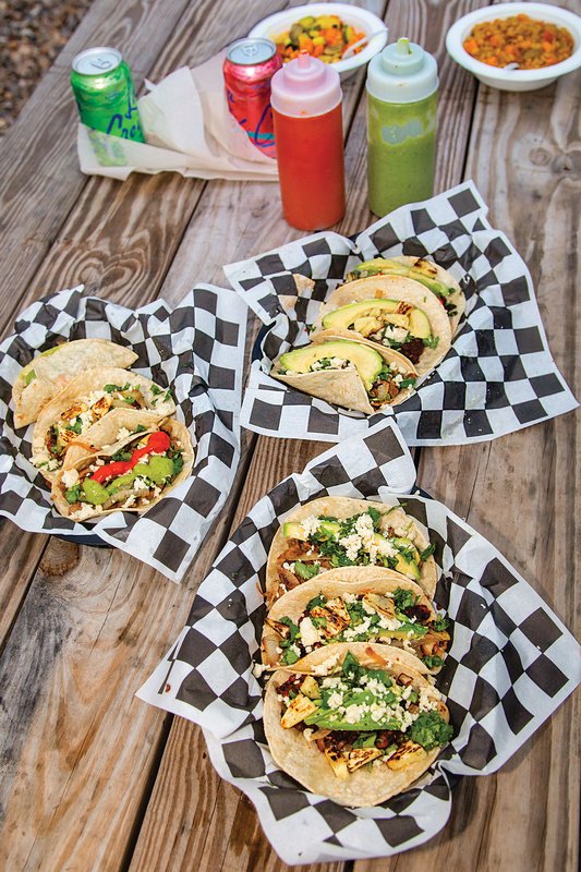 Tacos on plates on a picnic table.