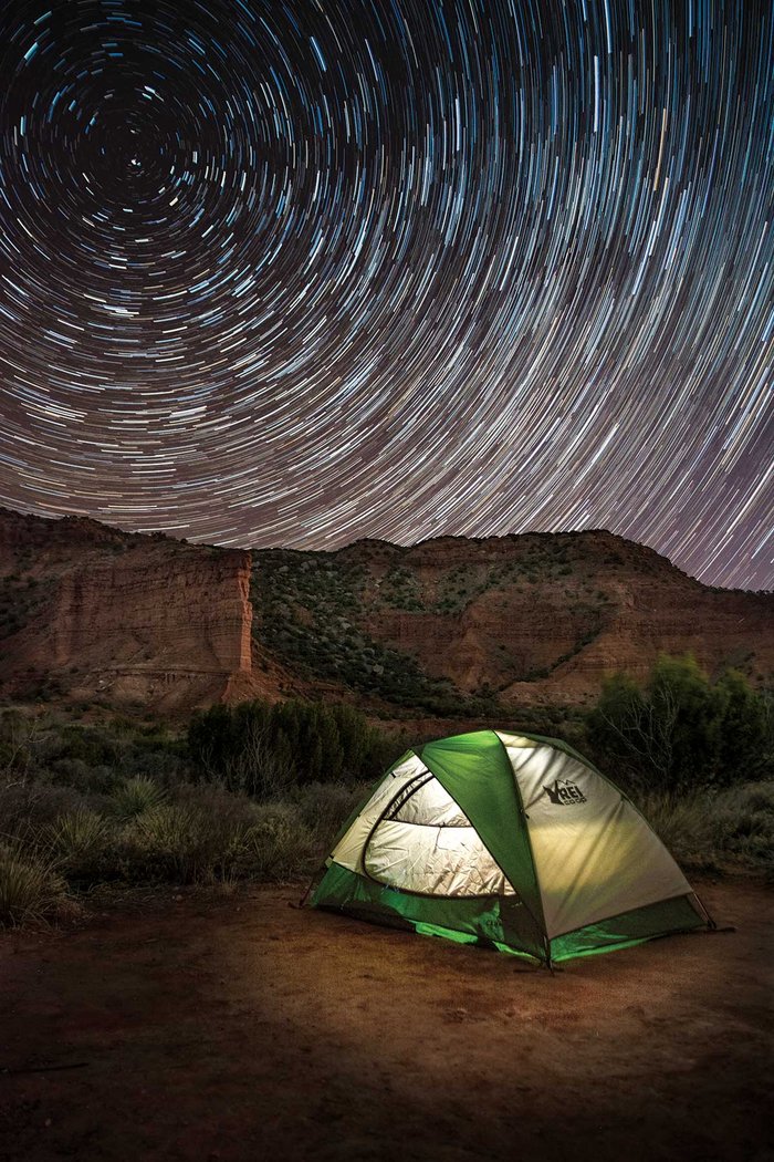 Tent in a canyon with a timelapsed night sky.