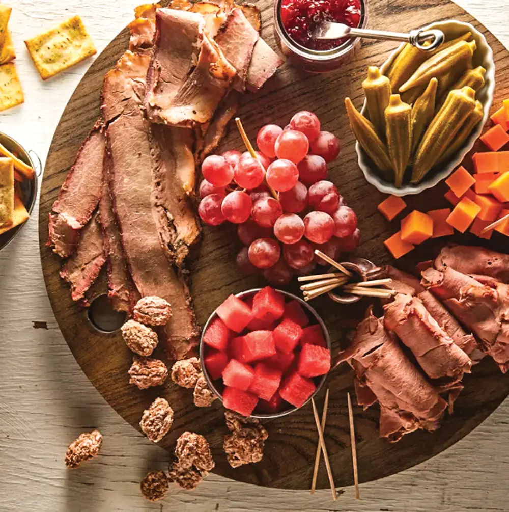 Texas Charcuterie Board containing watermelon, roast beef, brisket, cheese, and fruits on a cutting board.