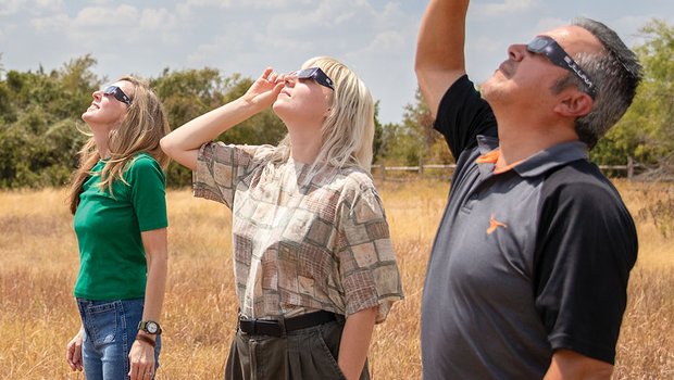 Three people looking to the sky with eclipse galsses