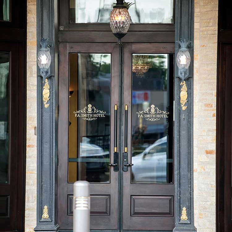 A pineapple-shaped chandelier hangs outside the tall glass doors of the restored P.A. Smith Hotel in Navasota