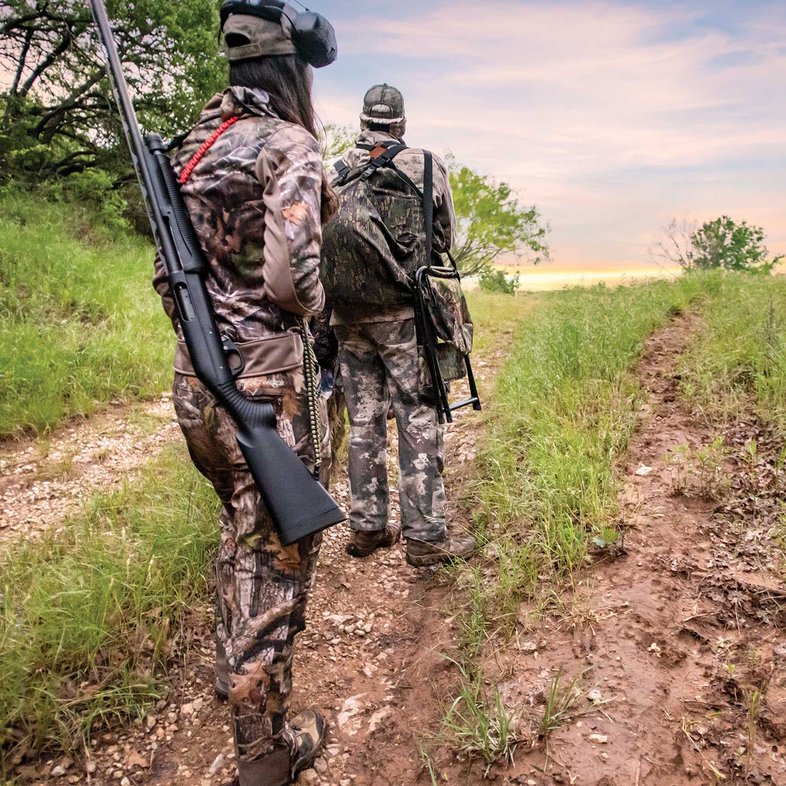 Two people walking on a trail ready for the turkey hunt.