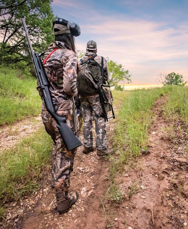 Two people walking on a trail ready for the turkey hunt.