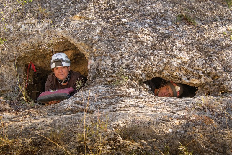 Two explores looking through holes from the inside of the cave to the outside.