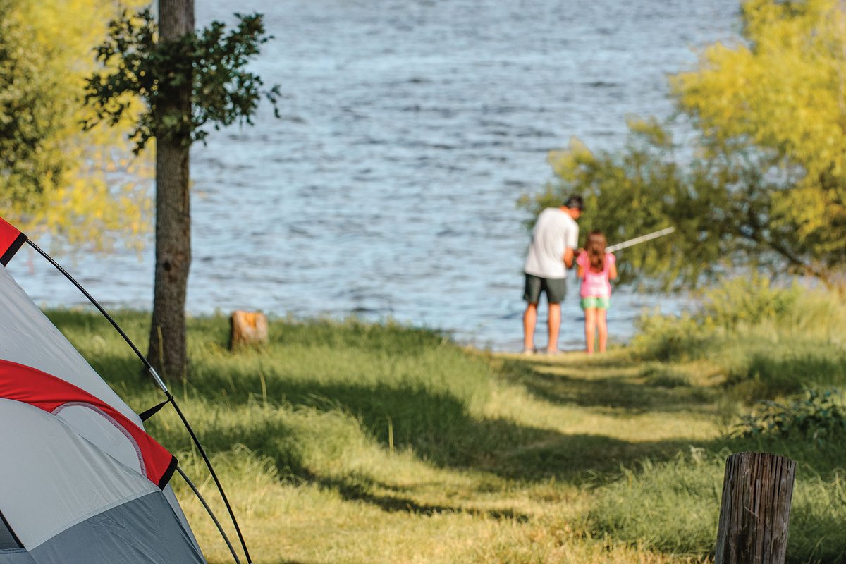 Two people fishing in a lake while camping