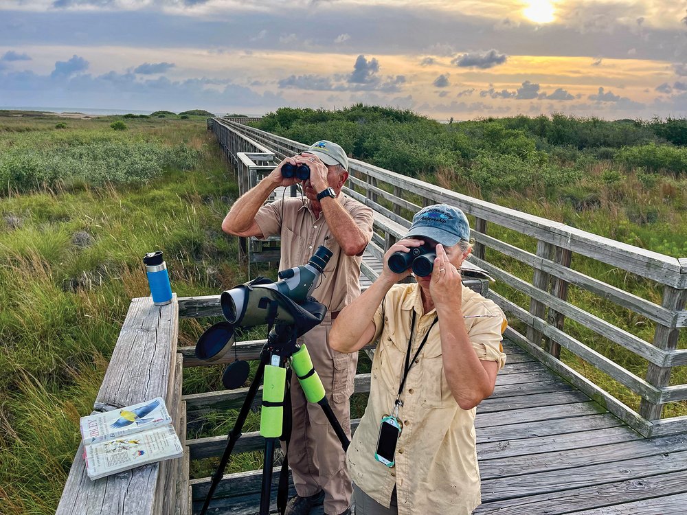 Two people looking through binoclars on an overlook at Port Oconnor