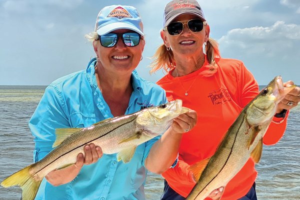Two women holding fish.