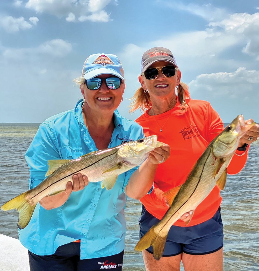 Two women holding fish.