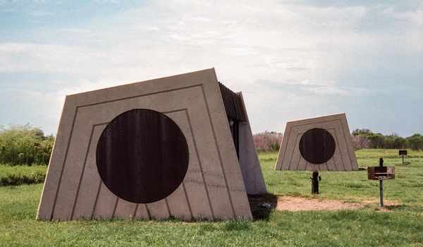 Picnic structure with concrete walls with a circular cutout.