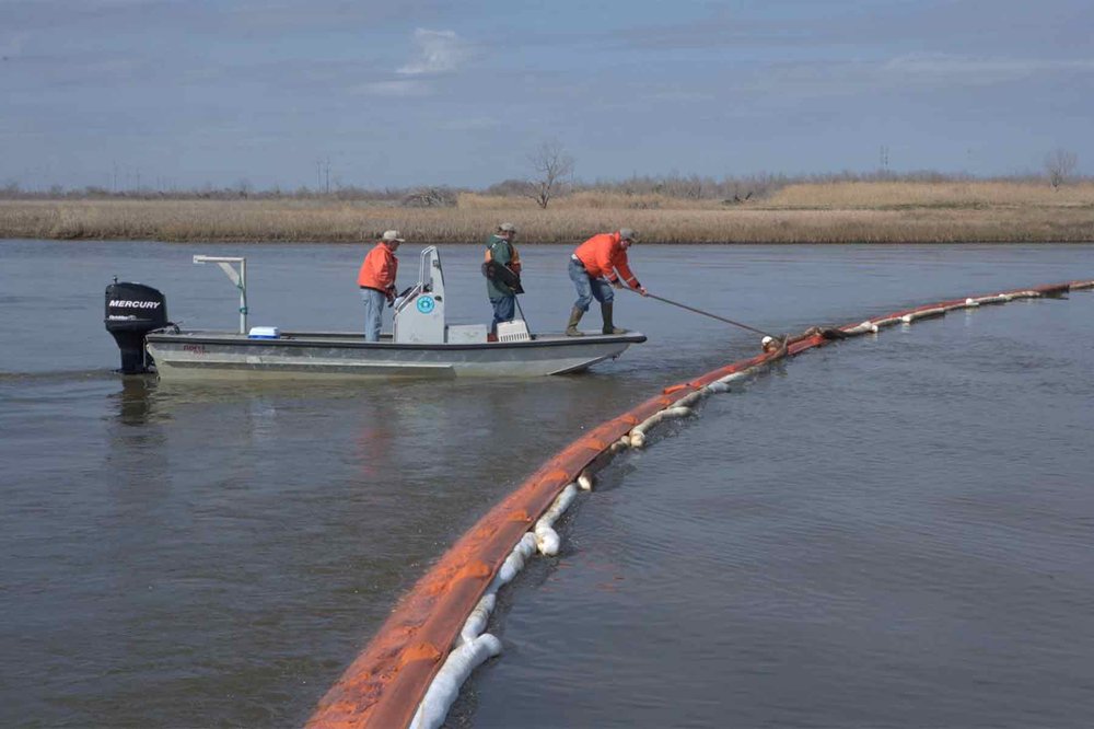Workers in a boat setting barriers to stop oil spill