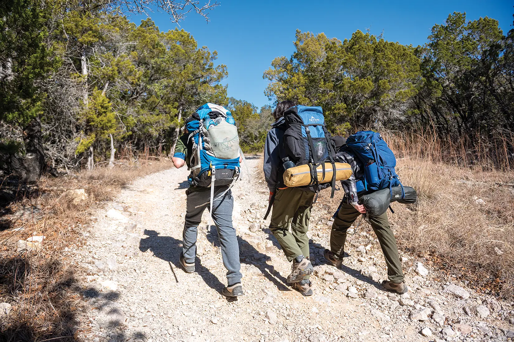 three people backpacking through the trails of pedernales falls