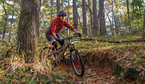 biker on a trail at Tyler State Park with tall pines flanking the trail