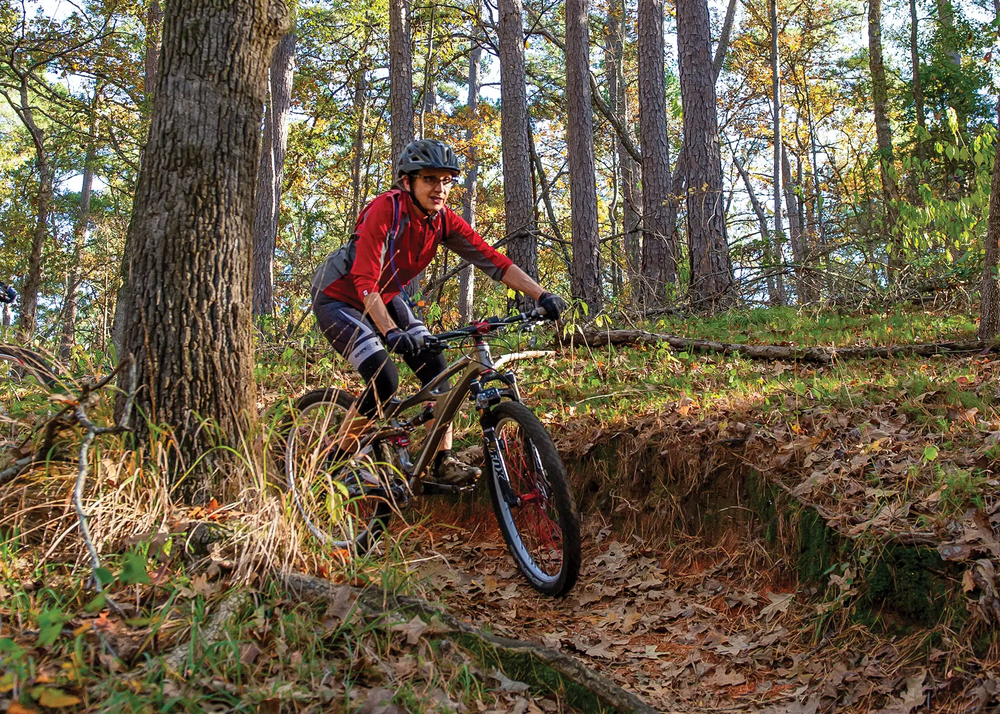biker on a trail at Tyler State Park with tall pines flanking the trail