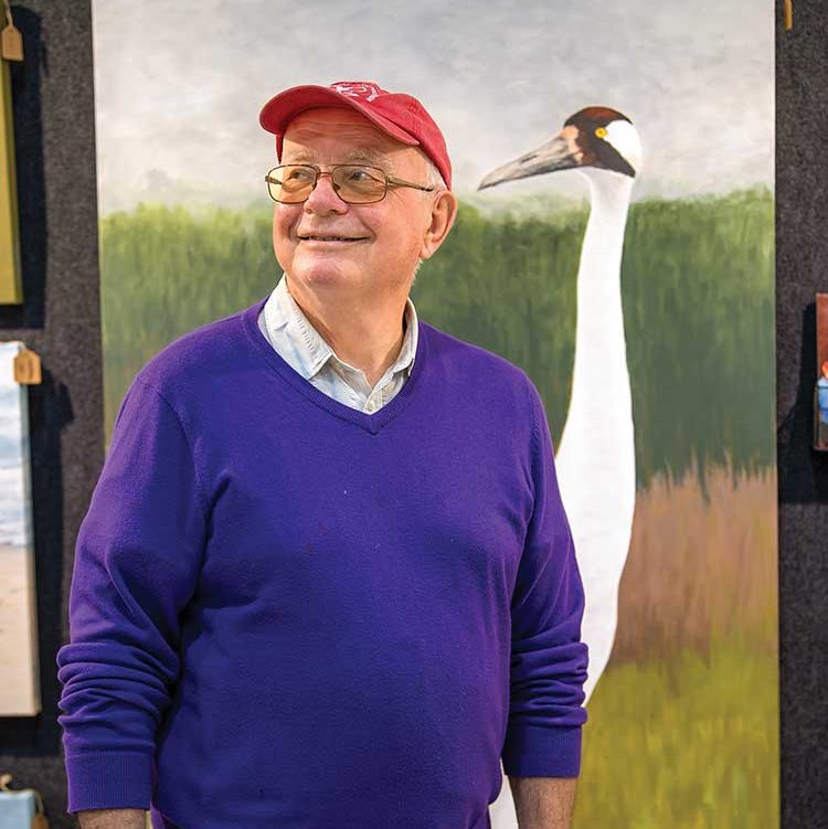 Birder poses in front of roseate spoonbill painting