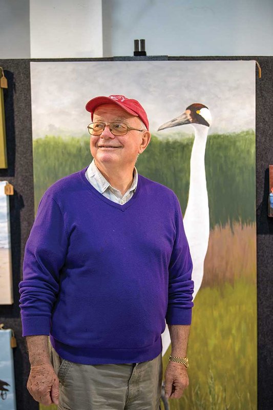 Birder poses in front of roseate spoonbill painting