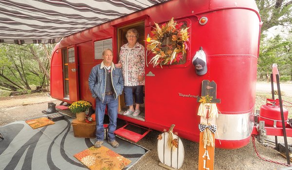 Two people next to a red trailer
