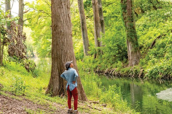 A woman stands by a river looking up