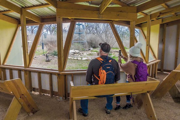 two people with backpacks on sitting in the davis mountains blind taking a picture