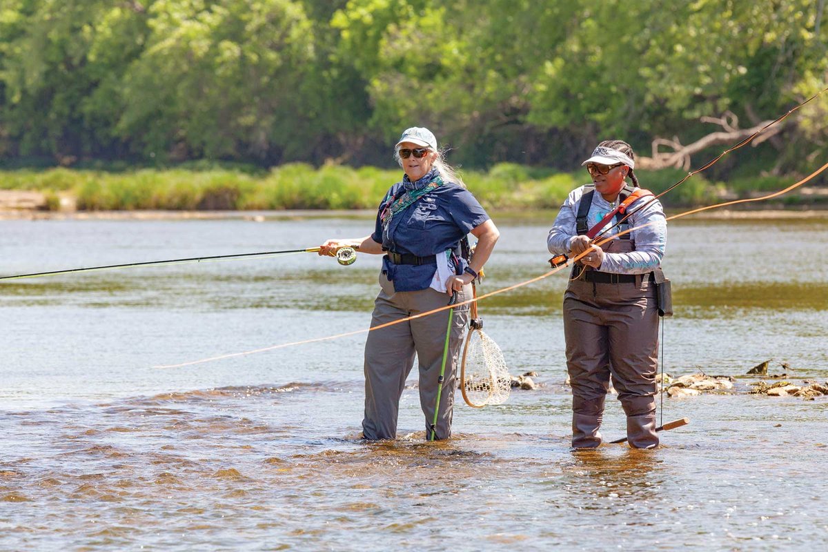 Two people fly fishing in ankle deep water.