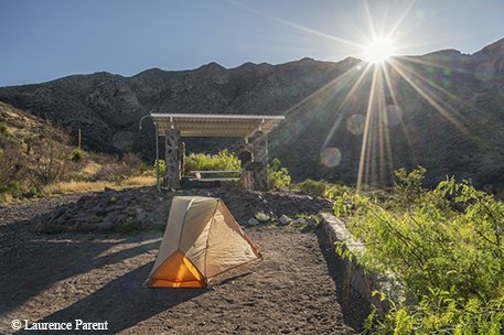 tent pitched near a pavilion with mountains in the background