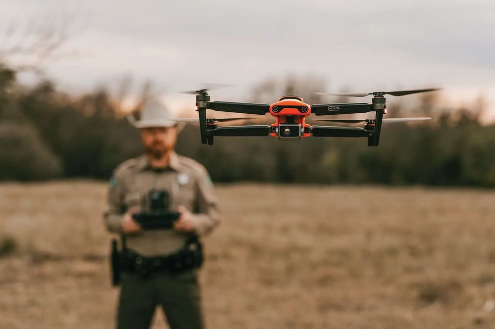 game warden using a drone flying it about heads height.