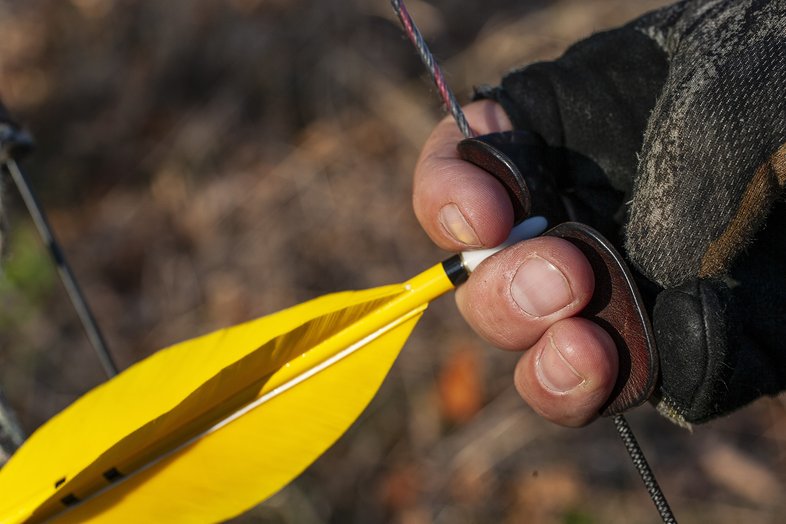 Hand on a yellow arrow in a bow.