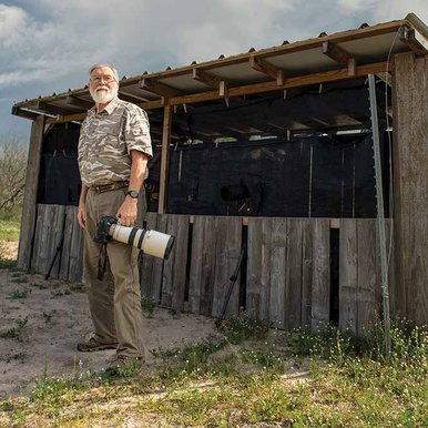 Hugh Lieck a photographer stands next to a hunting shack