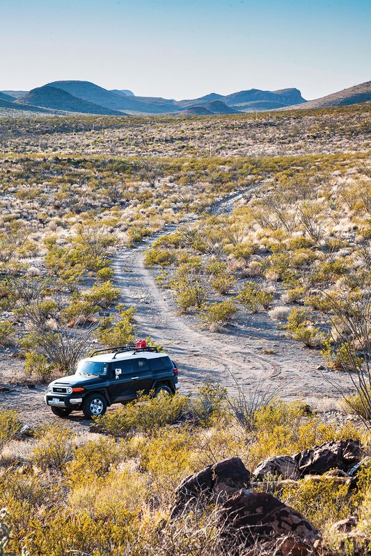 An SUV sits at the end of a dirt road in an arid wilderness area
