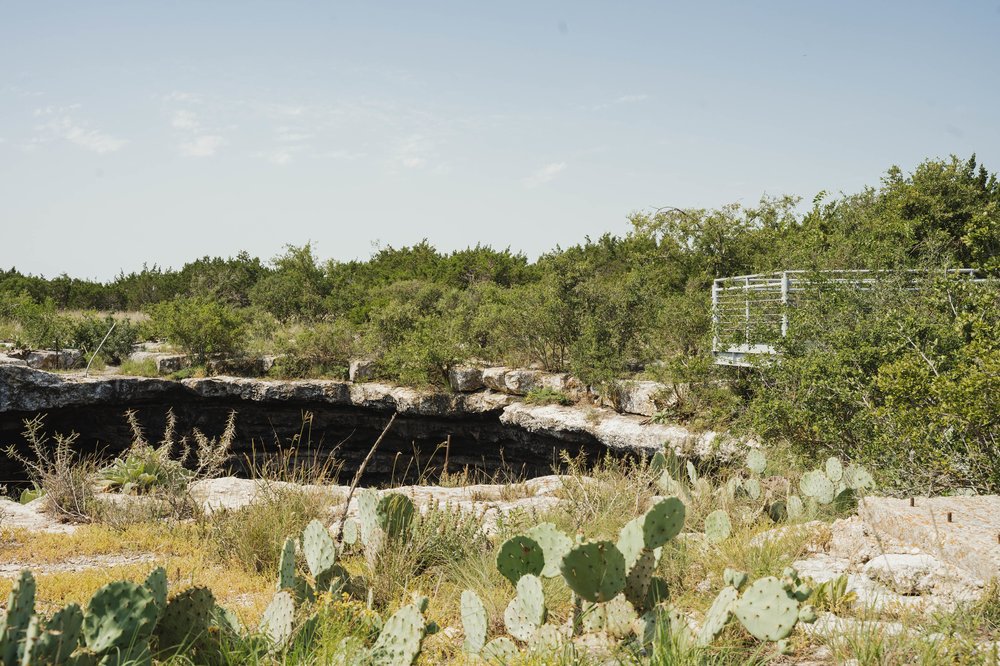 sinkhole surrounded by brush and cacti