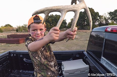 Lindsey Head's son plays with a set of antlers in the bed of a truck