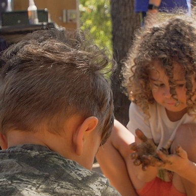 kids squatting while playing in the dirt while camping