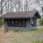 A grey blue cabin in the woods at Bob Sandlin State Park.
