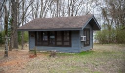 A grey blue cabin in the woods at Bob Sandlin State Park.