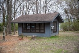 A grey blue cabin in the woods at Bob Sandlin State Park.