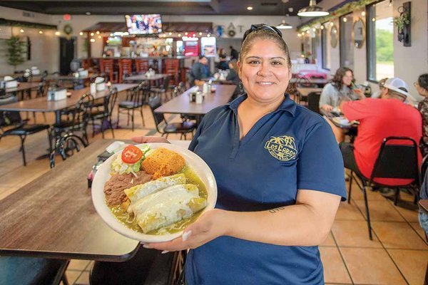 A woman holds a plate of food at Los Cabos