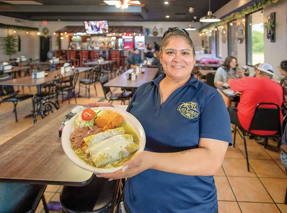 A woman holds a plate of food at Los Cabos