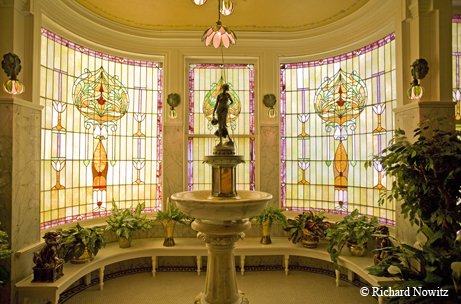 McFaddin-Ward House with stained glass windows, plants on a ledge and statue in the center