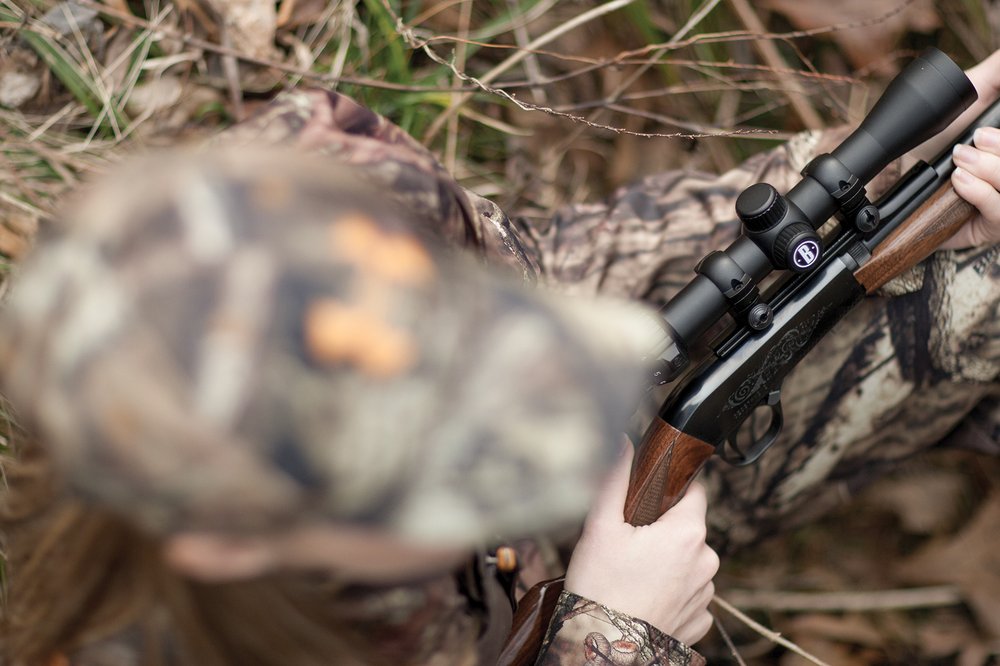 overhead view of a duck hunter wearing a hat and holding a gun.