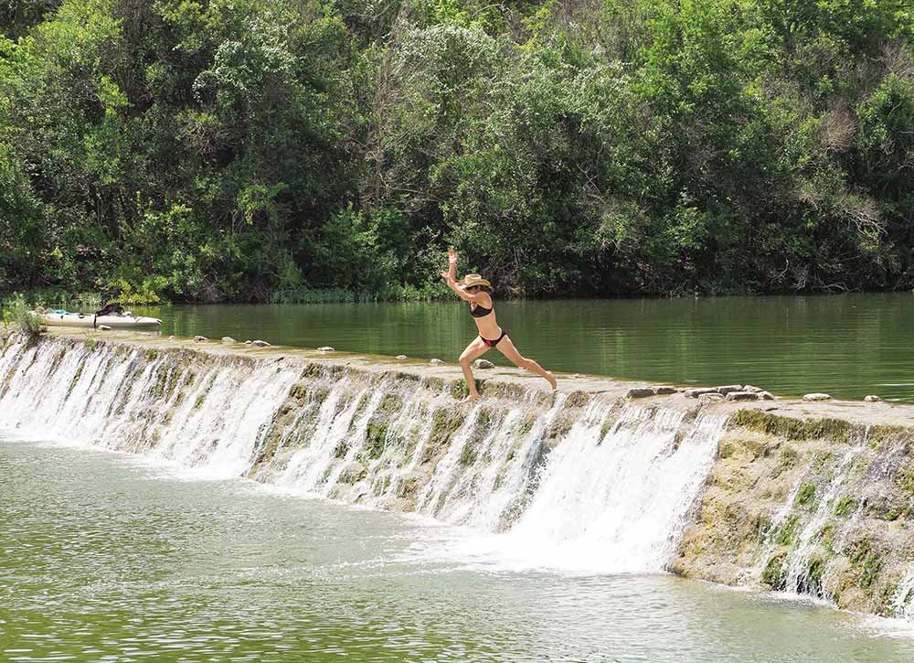 Swimmer jumping off the dam at Blanco State Park