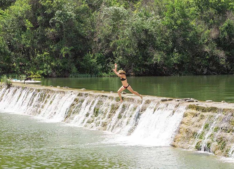 Swimmer jumping off the dam at Blanco State Park