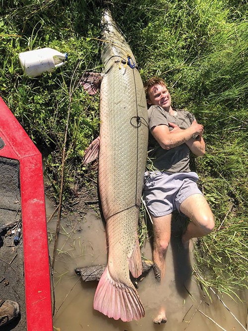 Paul Hefner lies next to an alligator gar he caught