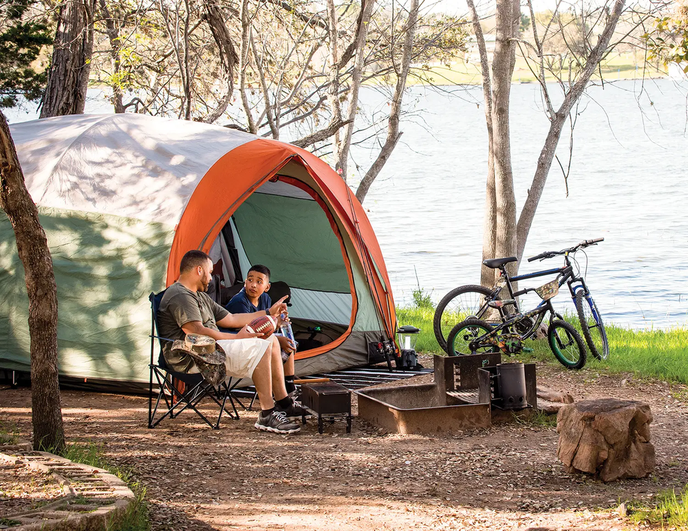 people sitting around a tent while camping with bikes leaning against a tree